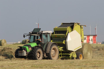 Tractor collecting haystack in the field