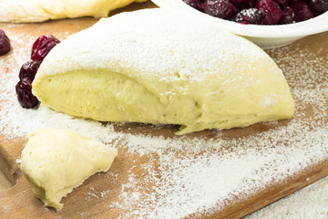 Ball of raw dough rising on floured wooden surface