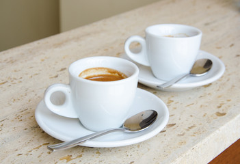 Two white espresso cups standing on the marble table