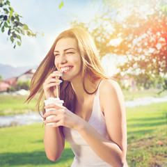 Beautiful happy young woman drinking coffee in park