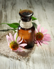 Medicine bottle with purple echinacea flowers on wooden table