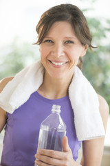 Happy Woman With Water Bottle And Towel Around Neck