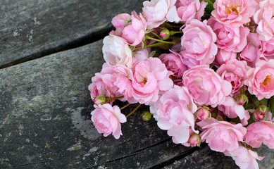 small pink garden roses on wooden surface