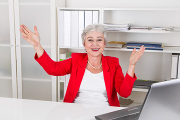 Seniorchefin - Frau mit grauen Haaren freut sich im Büro