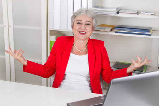 Lachende ältere Frau am Arbeitsplatz im Büro