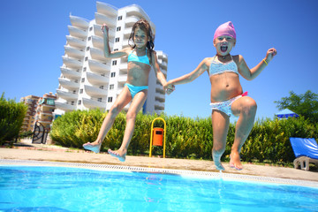 little girls holding hands fun jumping into swimming pool