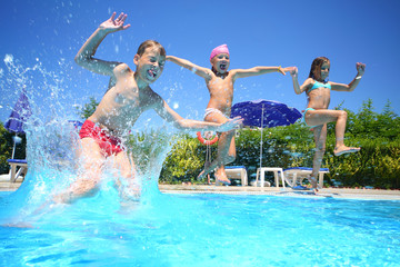 Two little girls and boy fun jumping into swimming pool - obrazy, fototapety, plakaty