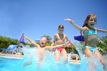 Two little girls and boy fun jumping into swimming pool