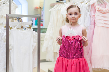 Fototapeta na wymiar Beautiful girl tries on a festive red dress in the store