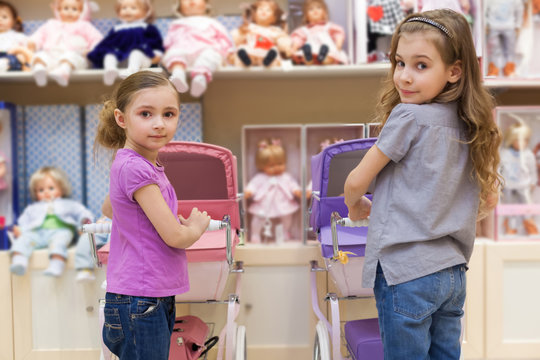 Two girls in toy store with rows of dolls  purchased buggy