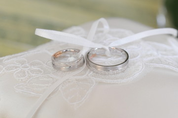 Closeup of silver wedding rings on a pillow