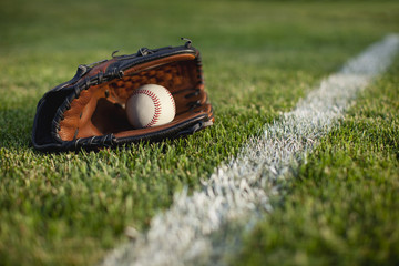 Baseball mitt and ball in grass by field stripe
