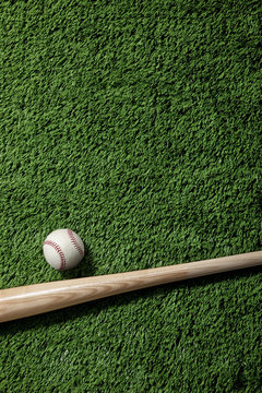 Overhead view of baseball and bat on green turf