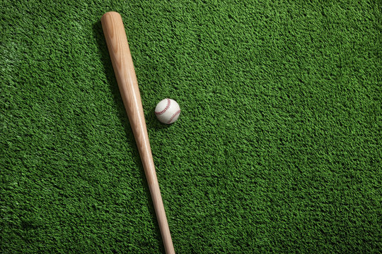 Baseball and bat on green turf viewed from above