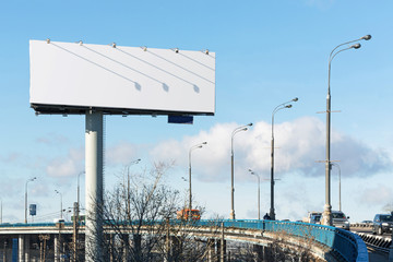 Cars driving on the bridge over the railway past a billboard