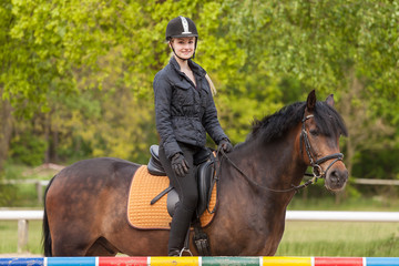 Mädchen sitzt auf ihrem Pony