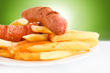 Fried sausage with french fries served on white plate - Powered by Adobe