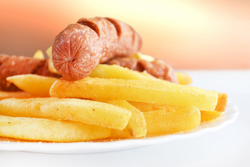 Fried sausage with french fries served on white plate
