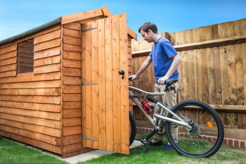 Obraz premium Man pushing his bike into a shed for storage