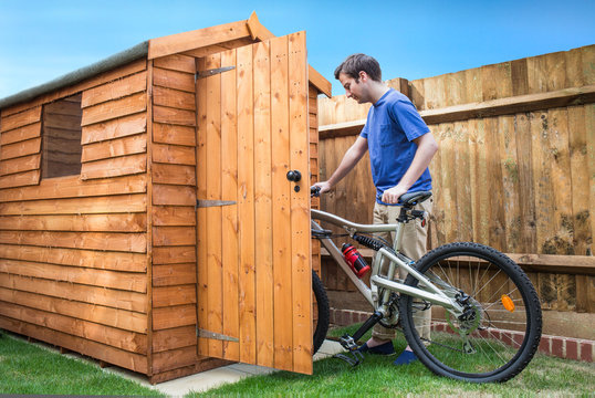 Man pushing his bike into a shed for storage