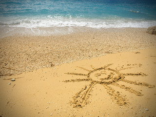 Drawing of the smiling sun on sand