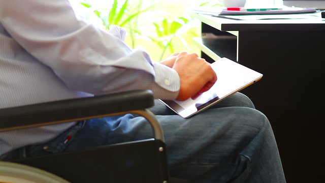 Office worker in wheelchair with tablet computer closeup