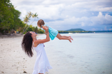 Young mother and her cute daughter have fun on exotic beach