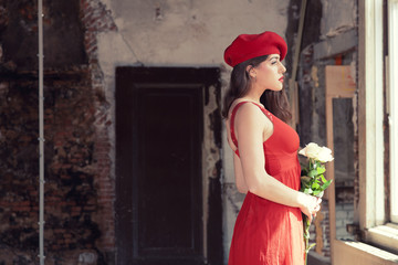 Sensual sexy bride wearing red dress and hat standing in old hou