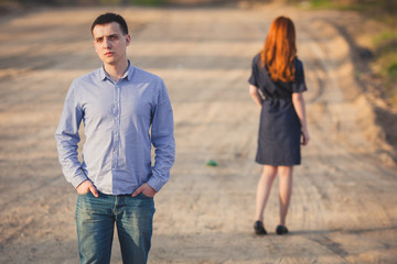 sad man and woman stand on the dirt road