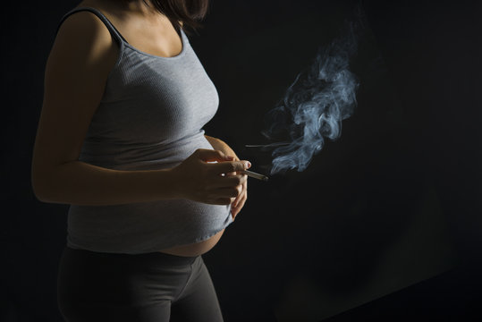 Smoker pregnant mother on a over dramatic dark light