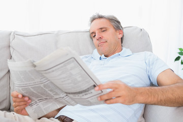 Obraz premium Man reading the newspaper on couch
