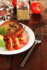 Piece of fried meat on plate on wooden table close-up