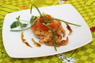 Vegetables and olive ornament on a fried fish