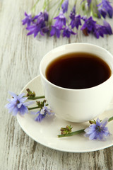 Cup of tea with chicory, on wooden background