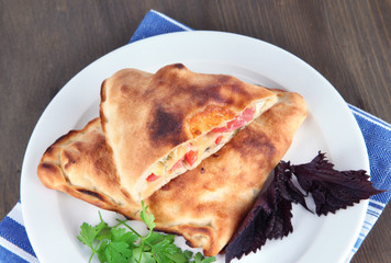 Pizza calzone on plate on napkin on wooden table