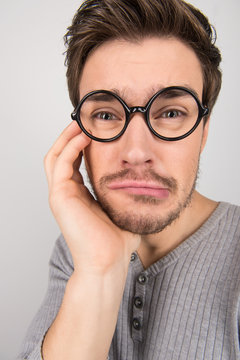 Depressed nerd. Portrait of young sad men in eyeglasses holding