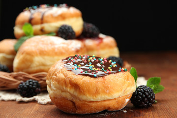 Tasty donuts with chocolate and berries on wooden table