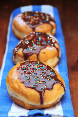 Tasty donuts with chocolate on wooden table