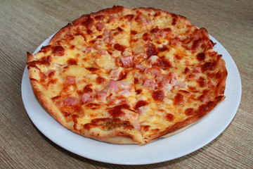 Closeup picture of pizza with ham, yellow cheese and pineapple