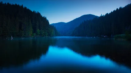 Fotobehang Blauwe sereniteit op een meer heel vroeg in de ochtend © bonciutoma