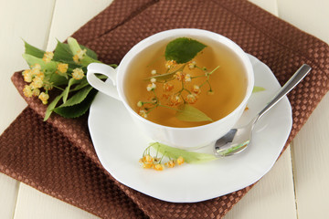 Cup of tea with linden on napkin on  wooden table
