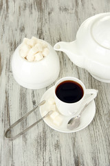 Cup of coffee, teapot and sugar-bowl on color wooden background