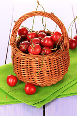Cherry berries in wicker basket on wooden table close up