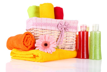 Colorful towels in basket and cosmetics bottles, isolated