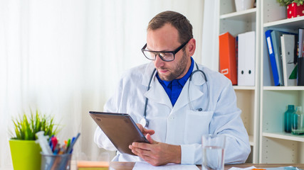 Young doctor using tablet in his  surgery.