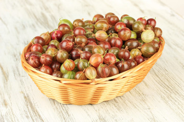 Fresh gooseberries in wicker basket on table close-up