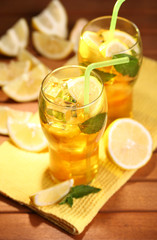 Iced tea with lemon and mint on wooden table, outdoors