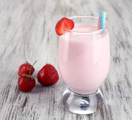 Delicious milk shake with strawberries on wooden table close-up