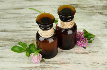 Medicine bottles with clover flowers on wooden table
