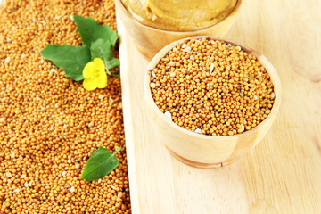 Mustard with seeds and mustard flower on wooden background